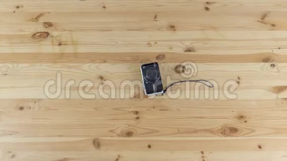 数码相机在木制桌子上的小三脚架上移动延时停止运动视频的预览图