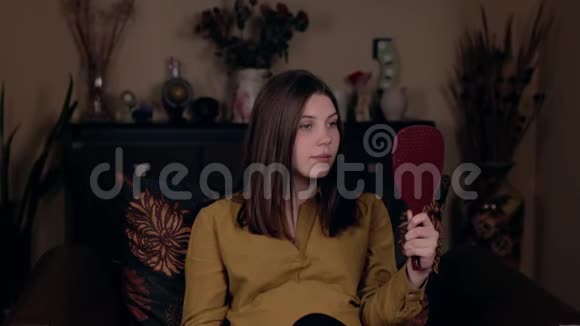 一个年轻的白人美女坐在扶手椅上对着镜子画着自己的嘴唇视频的预览图