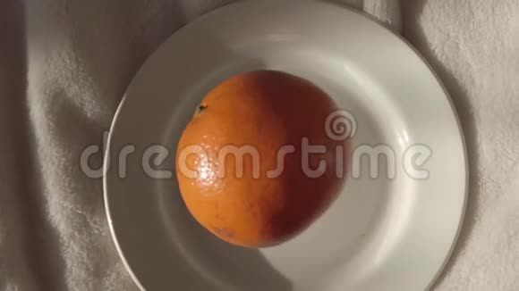 橘子慢慢地落在白色的盘子上视频的预览图
