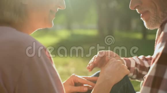 男性养老金领取者温柔地牵着女性的手在公园浪漫的约会特写视频的预览图
