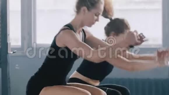 特写两个年轻有魅力的运动女性一起在健身房工作跳着大块头微笑着慢动作视频的预览图