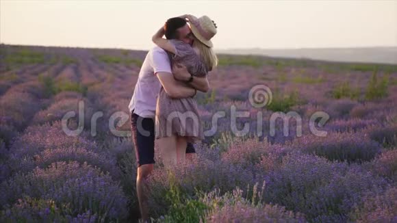 一个年轻人在他的手臂上盘旋他的女朋友在一片盛开的薰衣草花田里缓慢地运动着视频的预览图