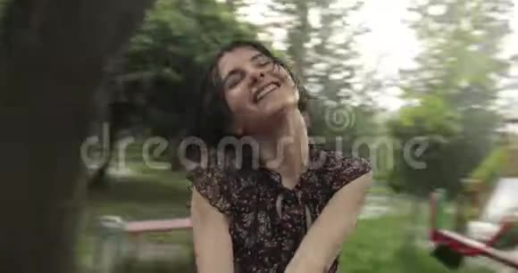 视频快乐迷人的女人在雨中的秋千上旋转有着深色短发的微笑女孩在这里玩得很开心视频的预览图