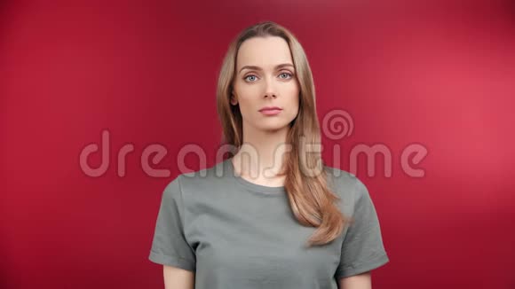 困惑青年女性在红色摄影棚背景下产生误解情绪的画像视频的预览图