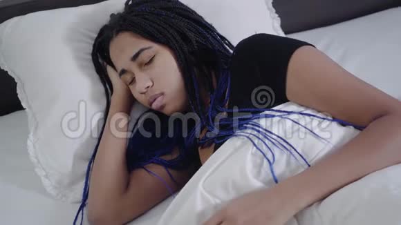 非洲裔美国女孩的最高视野与可怕的睡眠和固定毛毯年轻可爱的少年躺在白色的床上视频的预览图
