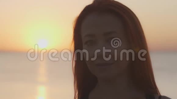 一个女人在海面黎明背景下的肖像视频的预览图