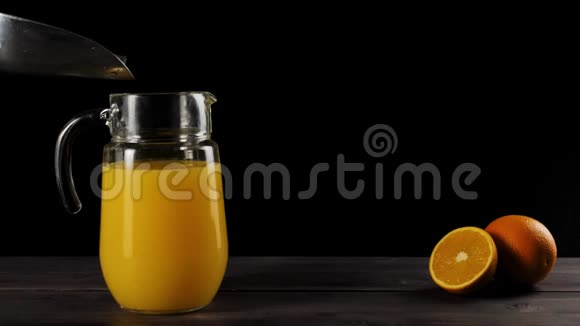 在木桌上用新鲜橙汁慢慢地从铲斗里掉出来的冰块视频的预览图