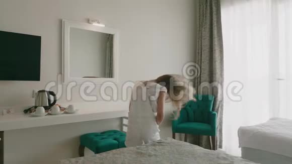 在度假酒店的卧室里快乐的女孩在跳舞开朗的女孩摇头和发前镜少女视频的预览图