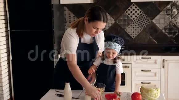 妈妈和女儿一起做饭在蔬菜沙拉里加盐视频的预览图