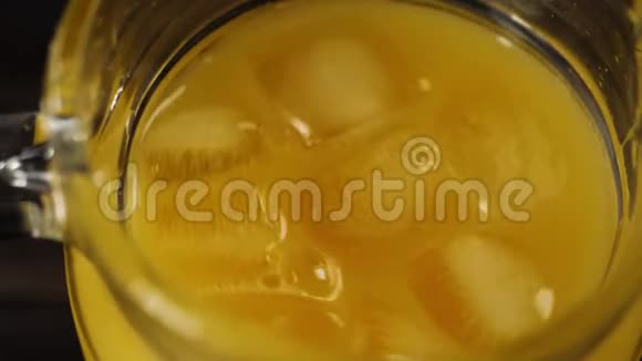 顶部看到冰块旋转和漂浮在新鲜橙汁在一个装饰器在桌子上视频的预览图