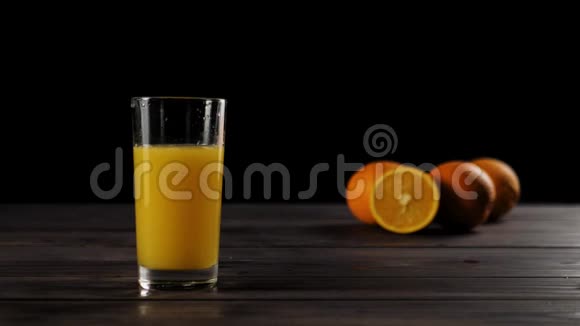 在一个高大的玻璃杯中倒入大量冰块加入新鲜橙汁在木桌上溅起水花和气泡视频的预览图