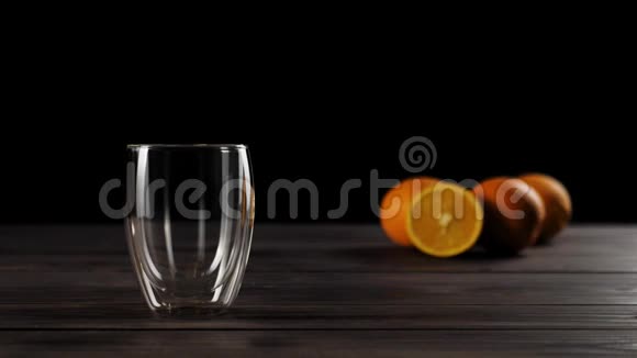 一张用软焦装饰着美味橙子的木桌上用双壁玻璃倒入新鲜橙汁视频的预览图