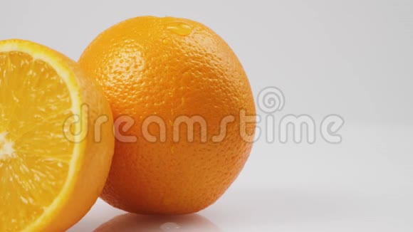 中间的一滴水慢慢地从白色桌子上流出一个新鲜的橘子在白色的背景下孤立地流动着视频的预览图