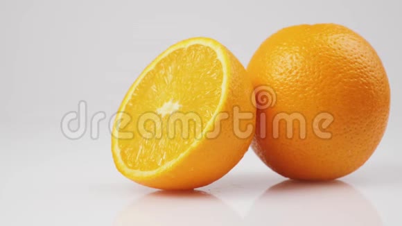 两个新鲜橙子的中间镜头在白色背景的白色桌子上旋转孤立地旋转视频的预览图