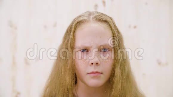 摄影棚灯光背景上的严肃少女肖像特写愤怒的女孩红色的头发和雀斑期待视频的预览图