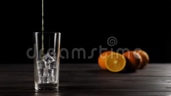 一张用美味橙子装饰的木桌上盛着冰块的高杯中注入一大杯新鲜橙汁视频的预览图