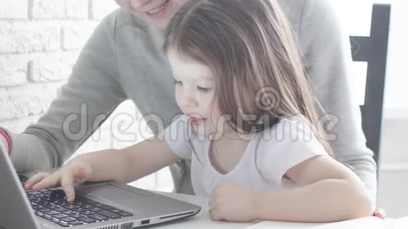 工作妈妈带着孩子在餐桌上忙碌的女人手里拿着婴儿在笔记本电脑上工作带着漂亮孩子的工作妈妈视频的预览图