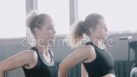 特写年轻迷人的白种人金发女人在健身房与个人女性健身教练慢动作视频的预览图