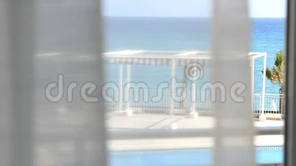 从一个人站在窗口观看蓝海或大海的视角拍摄的手持式镜头视频的预览图