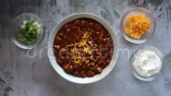 在一碗有豆子的辣椒里加入酸奶油和韭菜视频的预览图