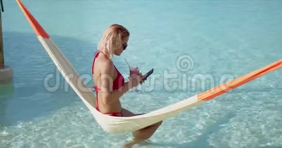 女游客喝鸡尾酒在吊床上自拍视频的预览图