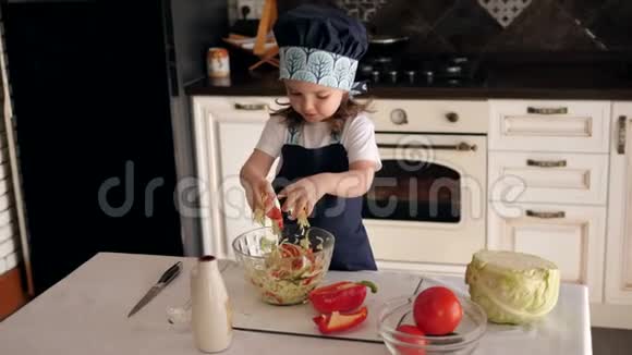 小女孩在厨房当厨师她用手拌蔬菜视频的预览图
