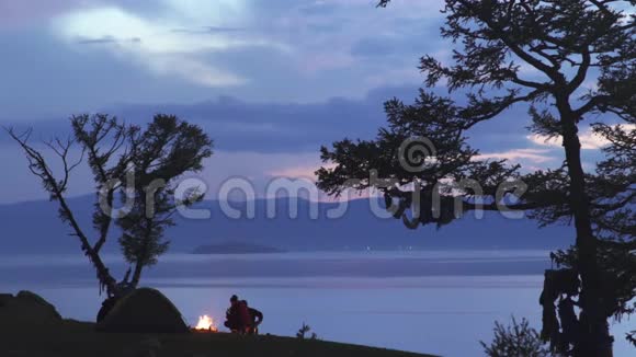 两个人在俯瞰俄罗斯贝加尔湖的篝火旁剪影视频的预览图