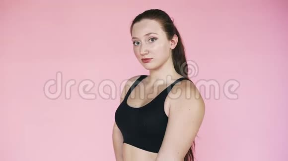 运动女孩在粉红色的背景上悬挂二头肌哑铃健身主题运动和健康的生活方式视频的预览图