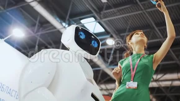 一个漂亮的女孩用机器人自拍机器人跟女人调情现代机器人技术机器人看着视频的预览图