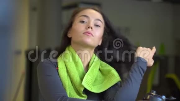 一个年轻漂亮的女孩在健身房里拿着绿色毛巾的肖像视频的预览图