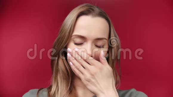 在红影院背景下疲惫的年轻女子手捂着嘴打哈欠的特写肖像视频的预览图