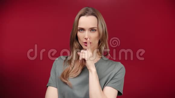 性感的休闲少女用手指对着嘴唇用手势示意红色背景视频的预览图