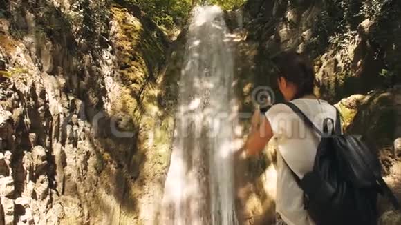 女人拍瀑布的照片视频的预览图