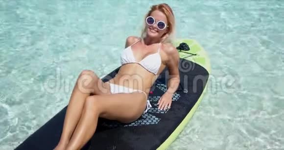 快乐的金发女人在桨板上日光浴视频的预览图