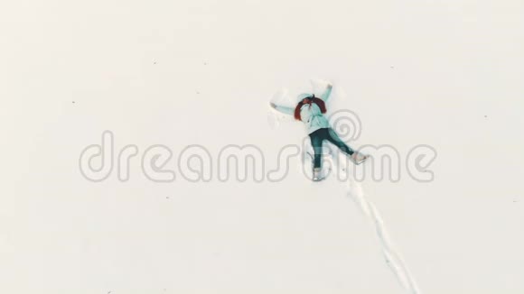 从空中俯瞰一位年轻女子她正在制作一个雪天使玩得开心视频的预览图