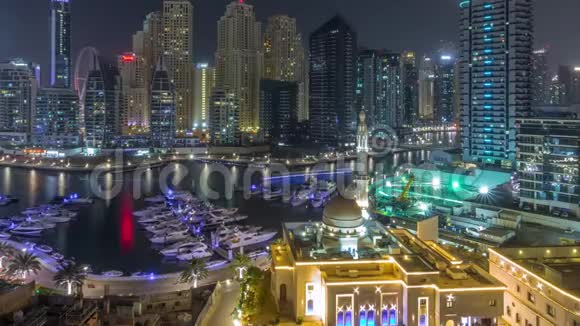 迪拜码头的游艇旁有AlRahim清真寺住宅塔和摩天大楼夜间时间推移视频的预览图