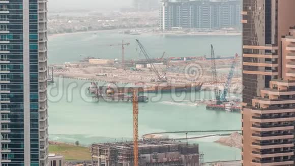 鸟瞰迪拜码头摩天大楼与建筑工地和棕榈朱梅拉岛背景时间推移视频的预览图
