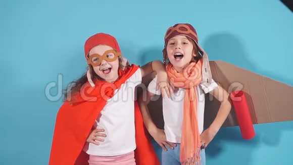 两个穿着飞行员服斗篷和纸板飞机的嬉戏的白种人儿童站在一起视频的预览图