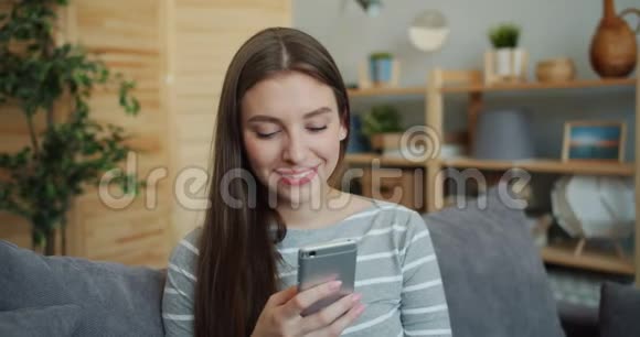 一幅美丽的女孩使用智能手机然后看着相机微笑的肖像视频的预览图