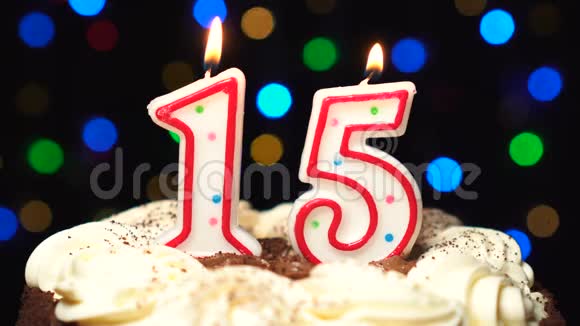 在蛋糕上面的15号15岁生日蜡烛燃烧在最后吹灭彩色模糊背景视频的预览图