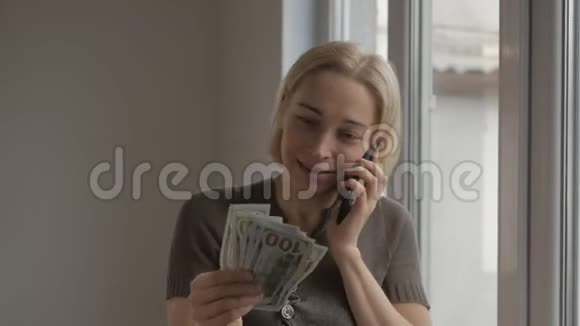女人站在窗口打电话拿着一包百元钞票视频的预览图