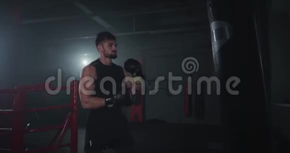 在一个大型的交叉健身班中一个强壮的年轻人带着完美的肌肉拳击而且集中地戴着拳击手套视频的预览图