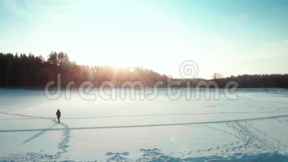 背包客在冬天穿过田野穿过冰湖视频的预览图