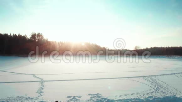 背包游客在冬天穿过田野日落景色视频的预览图