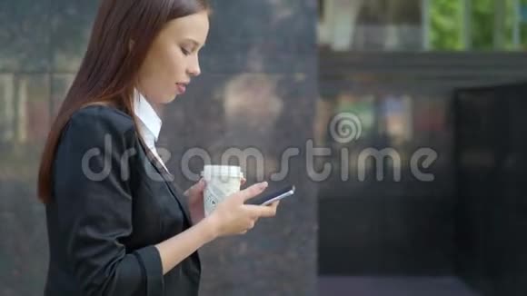 穿着商务服的女人走在街上手里拿着外卖的咖啡杯打电话发短信视频的预览图