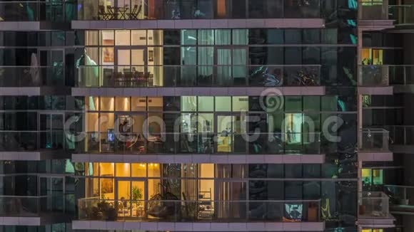 一排排发光的窗户晚上公寓大楼里的人视频的预览图