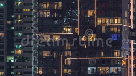 一排排发光的窗户晚上公寓大楼里的人视频的预览图