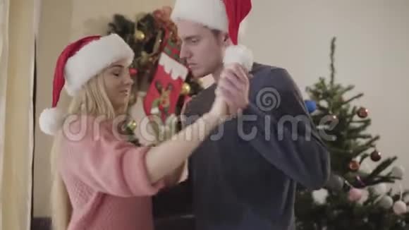 笑着白种人的男人和女人在家里的新年树前华尔兹快乐的年轻夫妇在一起视频的预览图