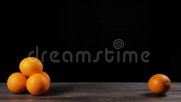 在黑色背景下一个橙色的面包卷穿过木桌在左边放着一堆橘子视频的预览图
