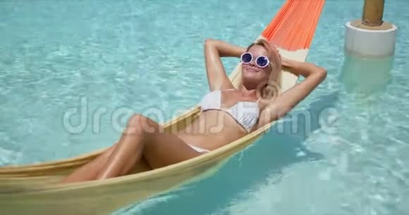 快乐的女人在游泳池的吊床上放松视频的预览图